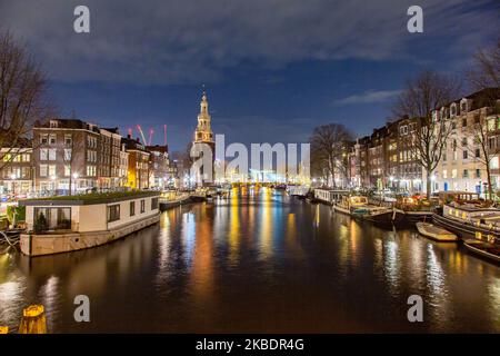 Grachten in Amsterdam wie Amstel mit typischen traditionellen alten niederländischen Architektur Häuser beleuchtet und Hausboote am Abend und Nacht mit schönen Wasserspiegelungen und Stadtlichter, Holland, Niederlande. Amsterdam ist ein Finanzzentrum, aber auch eine der meistbesuchten Städte Europas, die Millionen von Touristen auf der ganzen Welt anzieht, wobei der Tourismus eine wichtige Rolle in der lokalen Wirtschaft spielt, obwohl es Stimmen gegen diese touristische Entwicklung gibt. (Foto von Nicolas Economou/NurPhoto) Stockfoto