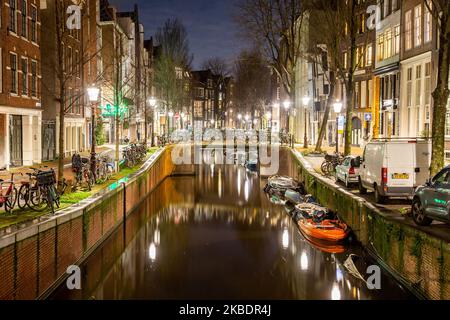 Grachten in Amsterdam wie Amstel mit typischen traditionellen alten niederländischen Architektur Häuser beleuchtet und Hausboote am Abend und Nacht mit schönen Wasserspiegelungen und Stadtlichter, Holland, Niederlande. Amsterdam ist ein Finanzzentrum, aber auch eine der meistbesuchten Städte Europas, die Millionen von Touristen auf der ganzen Welt anzieht, wobei der Tourismus eine wichtige Rolle in der lokalen Wirtschaft spielt, obwohl es Stimmen gegen diese touristische Entwicklung gibt. (Foto von Nicolas Economou/NurPhoto) Stockfoto