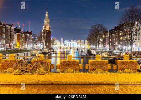 Grachten in Amsterdam wie Amstel mit typischen traditionellen alten niederländischen Architektur Häuser beleuchtet und Hausboote am Abend und Nacht mit schönen Wasserspiegelungen und Stadtlichter, Holland, Niederlande. Amsterdam ist ein Finanzzentrum, aber auch eine der meistbesuchten Städte Europas, die Millionen von Touristen auf der ganzen Welt anzieht, wobei der Tourismus eine wichtige Rolle in der lokalen Wirtschaft spielt, obwohl es Stimmen gegen diese touristische Entwicklung gibt. (Foto von Nicolas Economou/NurPhoto) Stockfoto