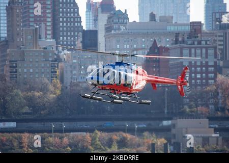 Ein rot-blauer Helikopter Bell 407GXP mit der Registrierung N777ZA von Zip Aviation voller Passagiere, wie man sieht, dass er auf dem Hubschrauberlandeplatz der New York Port Authority Downtown Manhattan Wall Street JRB KJRB Heliport-Plattform am Pier 6 im East River, Lower Manhattan in New York City landet, USA mit dem Fluss und den Gebäuden von Brooklyn im Hintergrund. Es ist eine beliebte Attraktion für Touristen, da sie mit den Sightseeing-Hubschrauberflügen eine Panoramaansicht von NYC erhalten. (Foto von Nicolas Economou/NurPhoto) Stockfoto