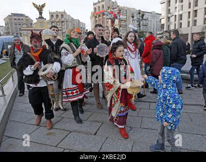 Ein Junge gibt den in Volkstrachten gekleideten Künstlern Geld, wenn sie während der Feier der orthodoxen Weihnacht auf dem Unabhängigen Platz in Kiew, Ukraine, am 7. Januar 2020 Weihnachtslieder singen. Die Ukrainer feiern den traditionellen Weihnachtstag mit Weihnachtsliedern und geschmückten Weihnachtssternen. (Foto von STR/NurPhoto) Stockfoto