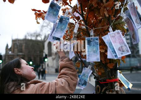 Eine Frau betrachtet die Parodie von 350m Banknoten, die das Gesicht von Premierminister Boris Johnson und dem führenden Brexit-Abgeordneten Jacob Rees-Mogg tragen, die an einem „Geldbaum“ befestigt sind, der am 7. Januar 2020 von Anti-Brexit-Aktivisten vor dem Parlament in London, England, aufgestellt wurde. Während der EU-Referendum-Kampagne 2016 behaupteten die Abgänger fälschlicherweise, dass jede Woche 350m in die EU geschickt würden, die stattdessen für den Nationalen Gesundheitsdienst ausgegeben werden könnten. Das Vereinigte Königreich wird die EU am 31. Januar um 11pm Uhr verlassen und beginnt eine Übergangsphase bis zum Jahresende, in der Zeit Premierminister Boris Stockfoto