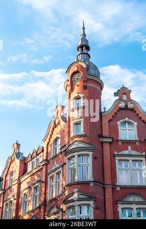 Das Gebäude des Rathauses aus dem Jahr 1904. Rote Ziegelfassade. Wunderschöner blauer Himmel. Die reich verzierte Fassade des Mietshauses. Siemianowice Śląskie Stockfoto