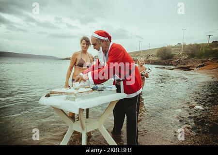 Die Winterschwimmer von Lavrio, einem Hafen im östlichen Attika, schneiden den Neujahrskuchen (Vasilopita auf Griechisch) für 2020. Menschen jeden Alters versammelten sich im neuen Jahr zum ersten Mal zum Schwimmen, bei einer Meerestemperatur von 12 bis 13 Grad Celsius. Danach hatten sie etwas Wein, traditionelle Bohnensuppe (Fasolada auf Griechisch) und gesungen. (Foto von Maria Chourdari/NurPhoto) Stockfoto