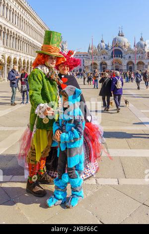 Venedig, Italien - 28. Februar 2022: Familie in Alice-Kostümen, auf dem Markusplatz, Teil des Karnevals der Maske von Venedig, Venetien, Italien Stockfoto