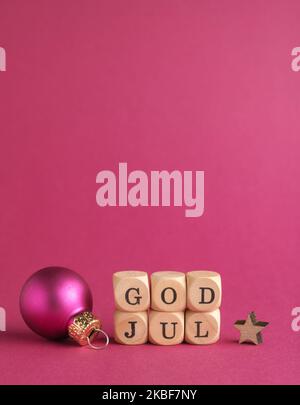 Kleine Holzblöcke mit der Aufschrift God Jul, Scandinavian Merry Christmas, lila Hintergrund, minimalistische Holzweihnachtsdekoration Stockfoto