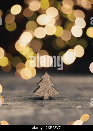 Kleine Holzbaumbauform mit verschwommenen Weihnachtslichtern, traditioneller Weihnachtskartenhintergrund, mit Platz für Text Stockfoto