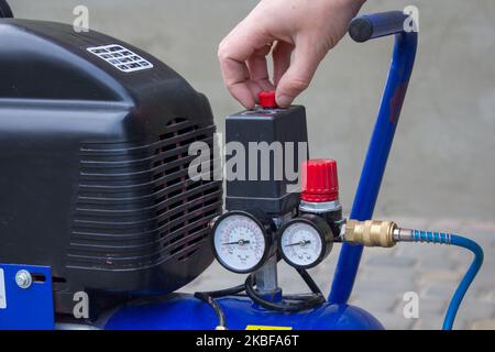 Starten des Luftkompressors mit der Hand im Hof Stockfoto