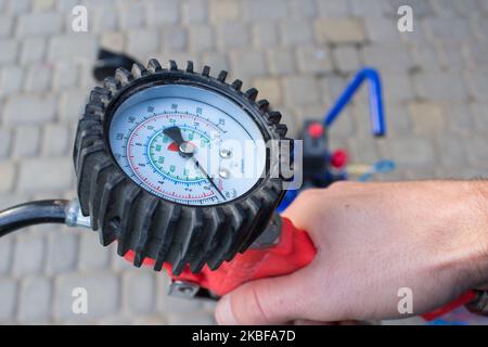 Mit den Händen halten Sie das Manometer zur Messung des Fahrzeugdrucks Stockfoto