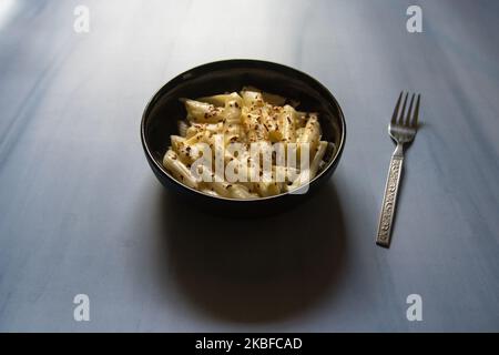 Draufsicht auf Pasta in weißer Sauce in einer Schüssel. Selektiver Fokus. Stockfoto