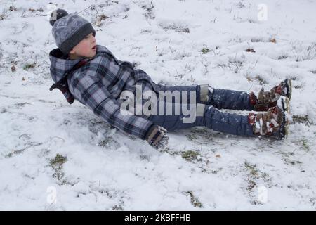 Winterferien sind glücklich, der Junge reitet von den Hügeln auf seinem Rücken Stockfoto