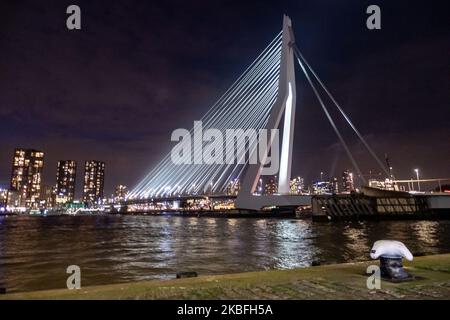 Erasmusbrug oder Erasmusbrug-Brücke, wie sie in der Nacht im Stadtzentrum der niederländischen Stadt Rotterdam am 20. Januar 2020 beleuchtet wird. Die 802m. Lange Brücke über das Wasser der Neuen Maas ist eine von Ben van Berkel entworfene, nach Desiderius Erasmus benannte Brücke mit Kabelgestellen und Bascule. Die Konstruktion und die Struktur sind berühmt für ihre moderne Architektur und das asymmetrische, blassblaue Pylondesign, das auch die größte Platte seiner Art in der Welt hat. Die Brücke ist ein Wahrzeichen, Denkmal für Rotterdam und die Niederlande. (Foto von Nicolas Economou/NurPhoto) Stockfoto