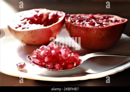 Nahaufnahme der Granatapfel-Fruchtkerne in einem Löffel auf einem Holztisch Hintergrund / Stillleben Stockfoto