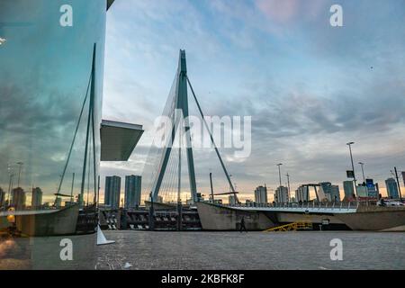 Erasmusbrug oder die Erasmus-Brücke, wie sie am 20. Januar 2020 in einer magischen Stunde am Winterabend mit buntem Himmel im Stadtzentrum der niederländischen Stadt Rotterdam, Niederlande, zu sehen ist. Die 802m. Lange Brücke über das Wasser der Neuen Maas ist eine von Ben van Berkel entworfene, nach Desiderius Erasmus benannte Brücke mit Kabelgestellen und Bascule. Die Konstruktion und die Struktur sind berühmt für ihre moderne Architektur und das asymmetrische, blassblaue Pylondesign, das auch die größte Platte seiner Art in der Welt hat. Die Brücke ist ein Wahrzeichen, Denkmal für Rotterdam und die Niederlande. (Foto von Nicolas Economou/NurP Stockfoto