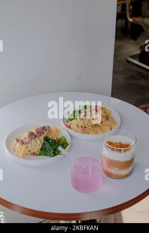 Vertikale oder Porträtaufnahme von zwei Getränken mit verschwommenen Rose Pasta Spaghetti als Hintergrund, enge Schärfentiefe Stockfoto