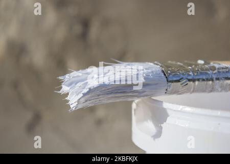 Weiß ist ein Pinsel in einem Eimer Farbe Nahaufnahme Stockfoto