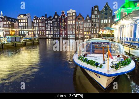 Die berühmten bunten Tanzhäuser mit authentischer holländischer Architektur säumen traditionelle Gebäude mit Lichtern. Die beleuchteten Häuser über dem Wasser am Damrak-Kanal-Becken sind eine berühmte Touristenattraktion, ein Wahrzeichen in der Nähe des Hauptbahnhofs, eine wichtige Touristenattraktion, in Amsterdam, Holland, den Niederlanden, wie sie nach Sonnenuntergang, während der magischen blauen Stunde, Dämmerung und Nacht gesehen werden. Amsterdam, Niederlande (Foto von Nicolas Economou/NurPhoto) Stockfoto