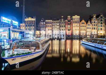 Die berühmten bunten Tanzhäuser mit authentischer holländischer Architektur säumen traditionelle Gebäude mit Lichtern. Die beleuchteten Häuser über dem Wasser am Damrak-Kanal-Becken sind eine berühmte Touristenattraktion, ein Wahrzeichen in der Nähe des Hauptbahnhofs, eine wichtige Touristenattraktion, in Amsterdam, Holland, den Niederlanden, wie sie nach Sonnenuntergang, während der magischen blauen Stunde, Dämmerung und Nacht gesehen werden. Amsterdam, Niederlande (Foto von Nicolas Economou/NurPhoto) Stockfoto