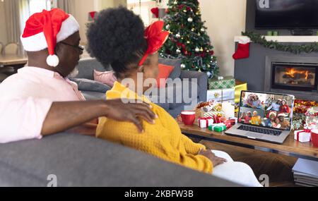 Ein afroamerikanisches Paar, das ein weihnachtliches Videogespräch mit verschiedenen Leuten führt Stockfoto