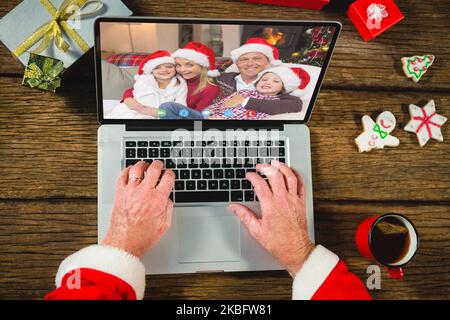 weihnachtsmann mit weihnachtsgeschenken, Videoanruf mit glücklicher, weißer Familie Stockfoto