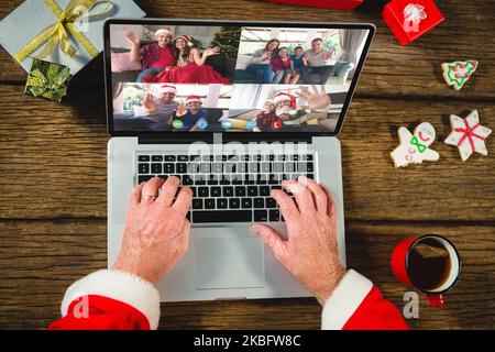 weihnachtsmann mit weihnachtsgeschenken, Videoanruf mit glücklicher, weißer Familie Stockfoto