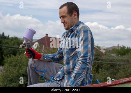 Dachdecker Bauarbeiter mit Pulverisierer Sprühen Farbe auf Metallblechdach Stockfoto