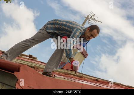 Dachdecker Bauarbeiter mit Pulverisierer Sprühen Primer vor dem Dach Stockfoto