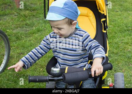 Kleiner Junge, der beim Radfahren die Hand auf dem Gras zeigt Stockfoto