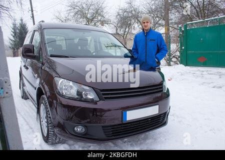 Der Mensch steht im Winter in der Nähe des gekauften Neuwagens Stockfoto