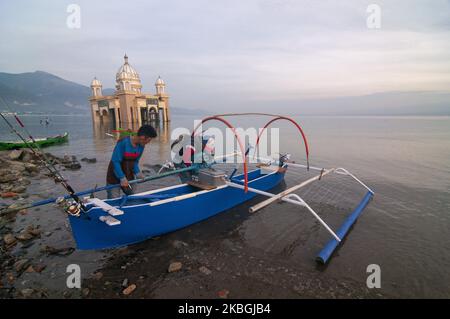 Fischer bereiten ihre Boote und Angelruten vor, um in der Nähe der schwimmenden Moschee, die am 9. Februar 2020 am Kampung Lere Beach, Palu, Central Sulawesi, Indonesien, ins Meer einstürzte, zu gehen. Die Lebenssituation in der Umgebung normalisiert sich allmählich, nachdem sie am 28. September 2018 von einem Tsunami getroffen wurde, bei dem Tausende von Einwohnern ums Leben kamen. Trotzdem verbieten die lokalen Behörden den Anwohnern, sich aufgrund von Katastrophengebieten dort umzusiedeln. (Foto von Basri Marzuki/NurPhoto) Stockfoto