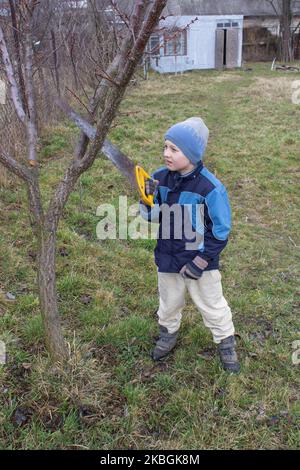 Kleiner Junge hilft im Garten, Äste zu schneiden Stockfoto