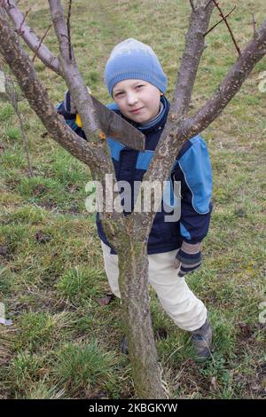 Junge eine Säge, die im Frühjahr Holz schneidet Stockfoto