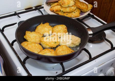 Gebratene Kartoffelpfannkuchen auf einer heißen Pfanne auf einem Gasherd Stockfoto