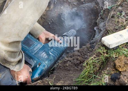 Hände arbeiten Ein Schlaghammer geht Pulver aus Beton Stockfoto