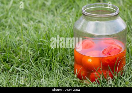 Öffnen Sie Tomaten aus der Dose auf dem Gras in einem Glas lecker Stockfoto