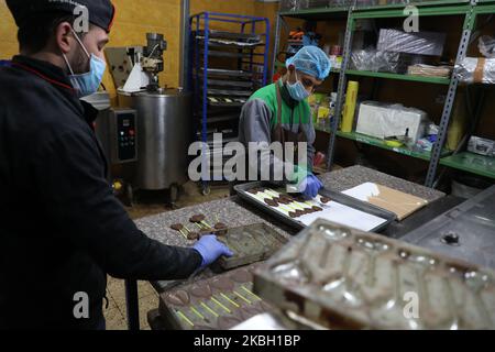 Am 15. Februar 2020 stellen Arbeiter der Süßwarenfabrik Alai in Gaza-Stadt mit Schokolade überzogene Süßigkeiten her. - Alai-Produkte sind aus dem Gazastreifen, aber ihre Bestandteile sind es nicht, da nur wenige der grundlegenden Rohstoffe im verarmten Küstenstreifen des Mittelmeers produziert werden. Israel kontrolliert alle Waren, die in den Gazastreifen gelangen, und verhängt eine Blockade, die sich verschärft, nachdem die kleine Enklave 2007 von der islamistischen Gruppe Hamas beschlagnahmt wurde. (Foto von Majdi Fathi/NurPhoto) Stockfoto