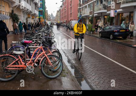 Menschen, die Fahrräder in der Stadt und/oder Ladestationen für Elektroautos in Amsterdam nutzen, gesehen am 17. Februar 2019. Amsterdam verfügt über ein breites Netz an Radwegen, die so sicher und komfortabel sind, dass auch Kleinkinder und ältere Menschen Fahrräder als einfachste Verkehrsmittel nutzen. Fahrräder werden häufig in anderen Städten wie Den Haag und Rotterdam eingesetzt. Benzin- und dieselbetriebene Autos und Motorräder werden ab 2030 aus Amsterdam verbannt, um die Luft der Stadt zu reinigen, sagte der Rat der niederländischen Hauptstadt 2019. Der Einsatz von Elektrofahrzeugen nimmt in der Stadt zu. Zum Aufladen ist ein Pass erforderlich Stockfoto