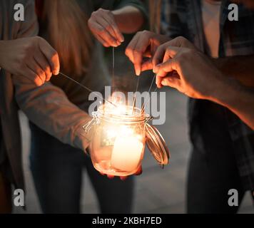 Feiern Sie die Menschen, die Sie glücklich machen. Eine Gruppe unkenntlich Völker Hände leuchten Funkler zusammen draußen in der Nacht. Stockfoto