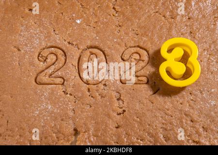 Die Zahlen des Jahres 2023 sind aus Lebkuchenteig für Weihnachtskekse und der Form der Zahl 3 ausgeschnitten. Wir bereiten hausgemachtes Lebkuchen zu. Cu Stockfoto