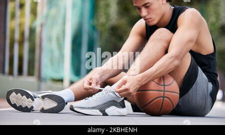 Basketballspieler, Schuhe und Sport zur Vorbereitung auf Spiel, Spiel oder Fitness auf dem Platz im Freien. Mann auf dem Basketballfeld, der Schuhe schnürt Stockfoto