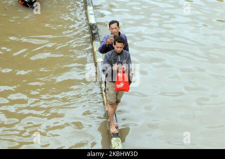 Menschen waten durch Hochwasser, nachdem am 25. Februar 2020 heftige Regenfälle in Jakarta, Indonesien, eintrafen. (Foto von Dasril Roszandi/NurPhoto) Stockfoto