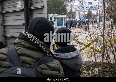 Am 29. Februar 2020 kamen Tausende von Flüchtlingen und Migranten am Grenzübergang Pazarkule zwischen Griechenland und der Türkei an und wurden trotz früherer Behauptungen des türkischen Präs Recep Tayyip Erdogan, dass er die Grenztore für Migranten aus Afghanistan, dem Iran, Pakistan und Syrien, nach einem Zusammenstoß mit syrischen Regimeeinheiten, bei dem mindestens 36 türkische Soldaten in der Provinz Idlib ums Leben kamen. Oben schauen zwei Männer, die versuchen, die griechische Grenze zu überqueren, über Stacheldraht auf griechische Polizeikräfte. (Foto von Diego Cupolo/NurPhoto) Stockfoto