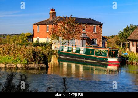 Ein Schmalboot, das vor einem roten gemauerten Haus in Caen Hill am Kennet & Avon Canal, bei Devizes, Wiltshire, England, vertäut ist Stockfoto