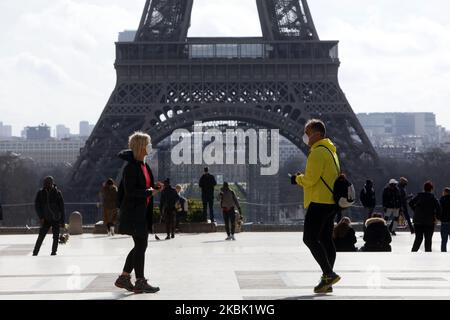 Ein Paar mit Schutzmaske gegen das Coronavirus läuft am 15. März 2020 vor dem Eiffelturm in Paris, Frankreich, während Frankreich gegen das Coronavirus kämpft, das die COVID-19-Krankheit verursacht. Frankreich und Spanien wurden zu den jüngsten europäischen Ländern, die Sperrungen verhängt hatten, während Australien Neuseeland beitrat und die Selbstisolierung für alle Ankommenden anordnete, da die Zahl der Coronavirus-Infektionen weltweit über 150.000 mit fast 6.000 Todesfällen stieg. Frankreich ordnete die Schließung von Restaurants, Bars, Kinos und Nachtclubs an - sagte aber, dass Lebensmittelgeschäfte, Apotheken und Banken weiterhin geöffnet bleiben würden und weiter vordrangen Stockfoto