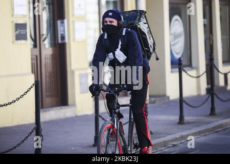 Ein Radfahrer mit Lebensmittelzustellung trägt eine Gesichtsmaske, die aufgrund der Ausbreitung des Coronavirus eine schützende Wirkung hat. Krakau, Polen, am 15. März 2020. Der polnische Premierminister hat eine epidemische Bedrohung eingeführt, die ab Samstag in Kraft tritt und Kontrollen an den Landesgrenzen sowie Beschränkungen für Dienstleistungen wie Museen, Restaurants, Pubs und Einkaufszentren umfassen wird. (Foto von Beata Zawrzel/NurPhoto) Stockfoto