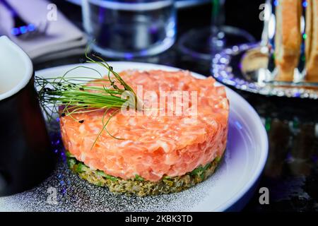 Lachstartare mit Avocado auf einem weißen Teller in einem Restaurant. Nahaufnahme, selektiver Fokus Stockfoto