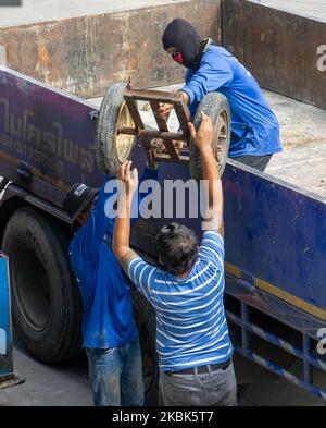 SAMUT PRAKAN, THAILAND, SEP 16 2022, Arbeiter entladen einen Wagen aus dem Ladebett eines Lastwagens Stockfoto