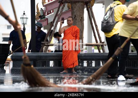 Ein Mönch lebt auf Facebook, während die Reinigungsmitarbeiter am 18. März 2020 die Gegend des Wat Rakhang Khositaram Tempels in Bangkok, in Bangkok, Thailand, reinigen. (Foto von Vachira Vachira/NurPhoto) Stockfoto