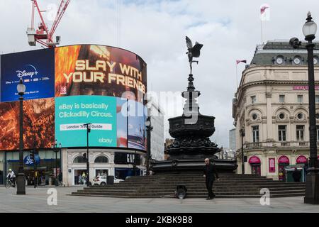 Ein Pantomime-Künstler spielt von Shaftesbury Memorial Fountain aka. „Eros“ im fast menschenleeren Piccadilly Circus im Zentrum von London, während die Coronavirus-Pandemie am 20. März 2020 in London, England, weiter eskaliert. Die Isolation der Haushalte, die soziale Distanzierung, die Arbeit von zu Hause aus, die Vermeidung öffentlicher Versammlungen wurden empfohlen, während die öffentlichen Verkehrsmittel als Teil der Schutzmaßnahmen reduziert wurden, um die Ausbreitung der Krankheit zu verringern. Die Regierung beschloss, Schulen in ganz Großbritannien ab Montag zu schließen und gesetzgeberische Coronavirus-Gesetz, das öffentliche Gesundheit, Einwanderung und Polizisten Befugnisse gibt t Stockfoto