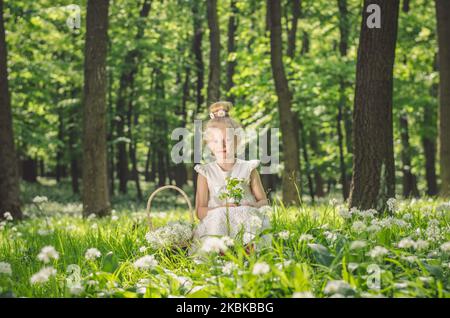 Liebenswert blonde Mädchen im Frühlingswald mit weißen blühenden Blumen Stockfoto